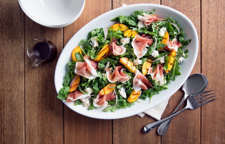 Arugula salad with grilled oranges, Parmesan cheese and slices of prosciutto served with fig jam dressing on the side