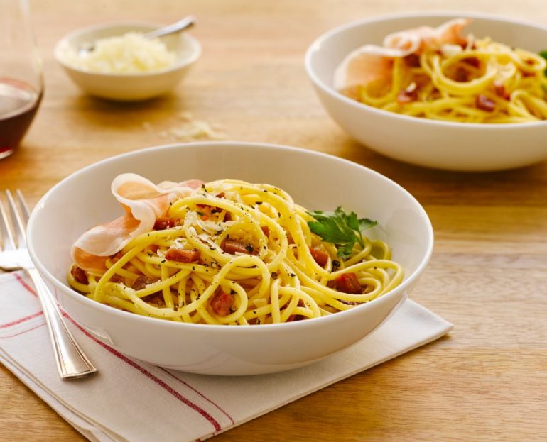 Spaghetti Carbonara with Prosciutto in a white bowl, ready to eat